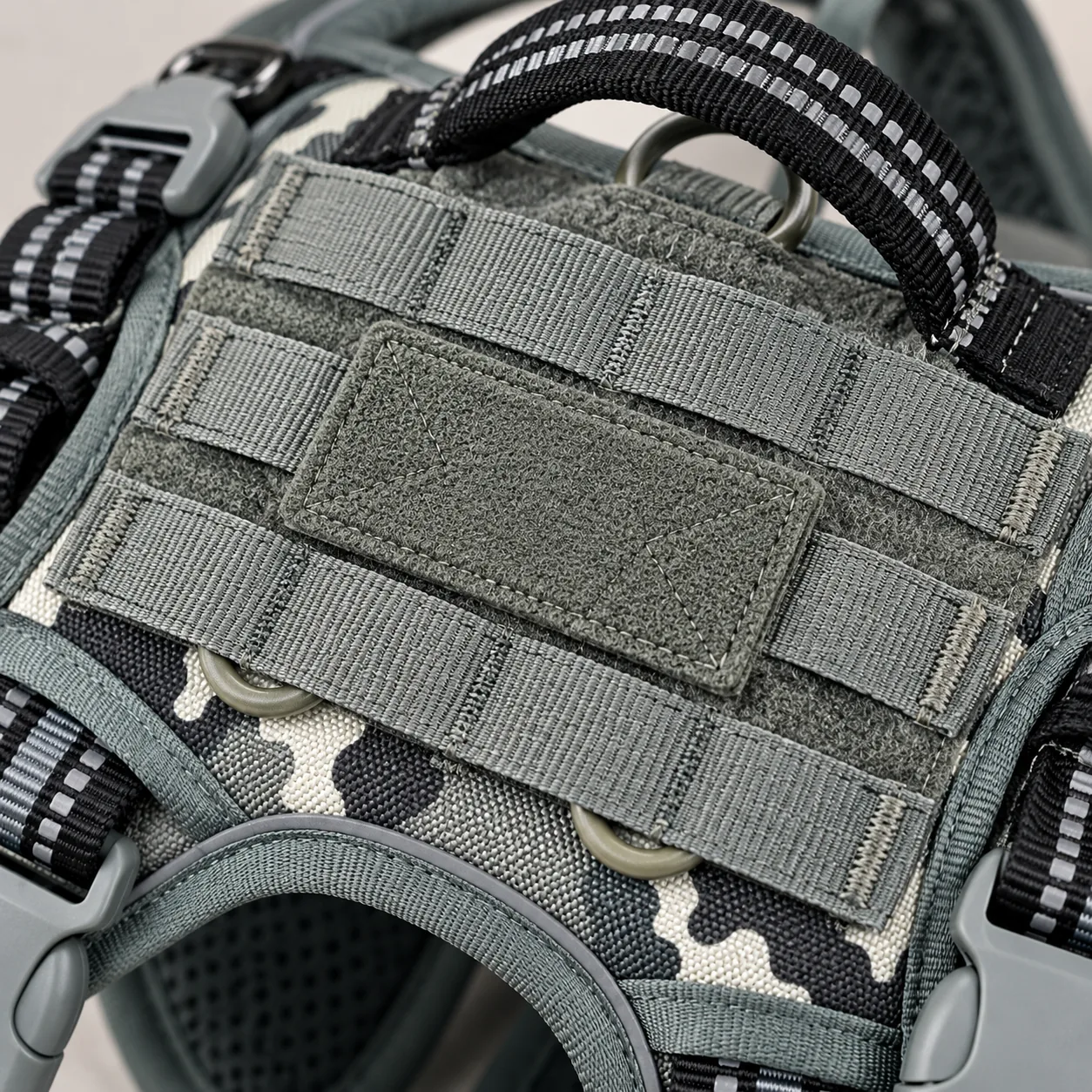 Macro of the MOLLE panel on the harness back: rows of stitched webbing over a hook-and-loop field, with a blank patch pressed onto the centre